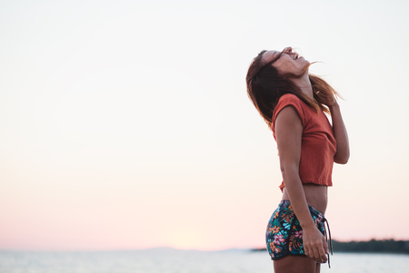 Young woman enjoying sunset by the seaの写真素材