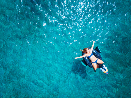 Aerial view of woman floating on the water mattress in the turquoise seaの写真素材