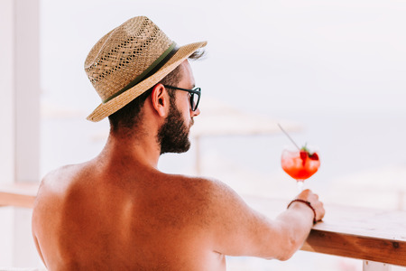 Young man enjoying cocktail in a beach barの写真素材