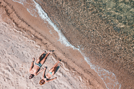 Young couple alone on the beach enjoying the view at the seaの写真素材