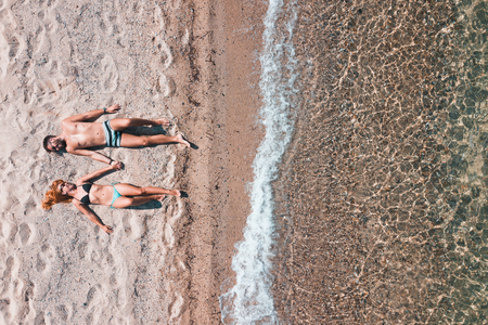 Young couple alone on the beach enjoying the view at the seaの写真素材