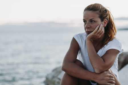 Young woman feeling sad by the seaの写真素材