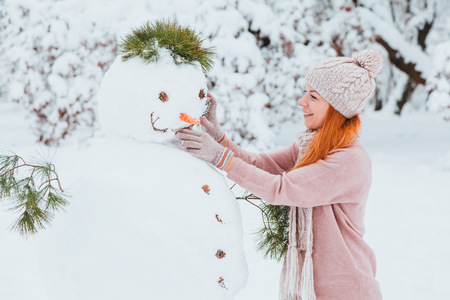 Young woman making snowman in the parkの写真素材