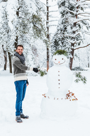 Young man making snowman in the parkの写真素材