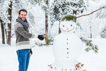 Young man making snowman in the parkの写真素材