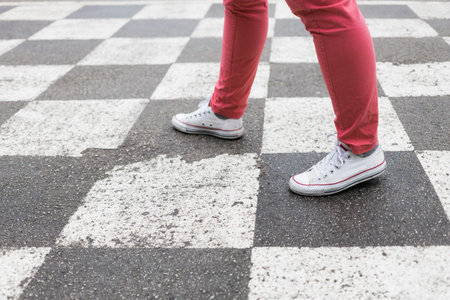 Concept with human legs standing on a chess board