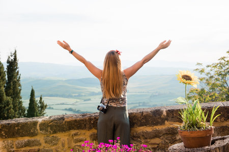 Young woman standing with her arms stretched enjoying the view of the Tuscany landscape