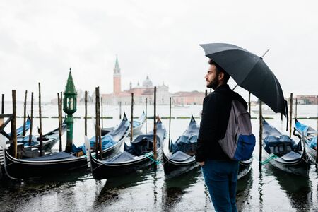 Young traveler in Venice, Italy standing by the canal on a rainy dayの写真素材