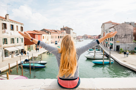 Young woman enjoying the view of the canal in Murano, Venice in Italyの写真素材