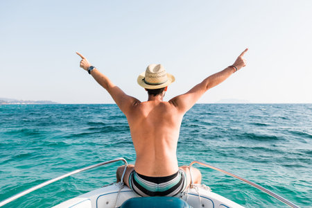 Young man on the bow of the boat enjoying the view of the sea