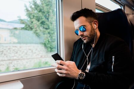 Young man traveling by train wearing earphonesの写真素材