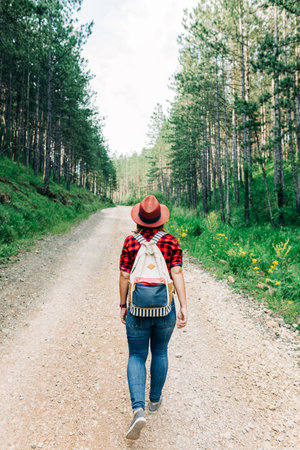 Young female nature explorer walking on mountain dirt road