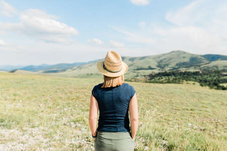 Young female nature lover enjoying the view of a mountain range in summertimeの写真素材
