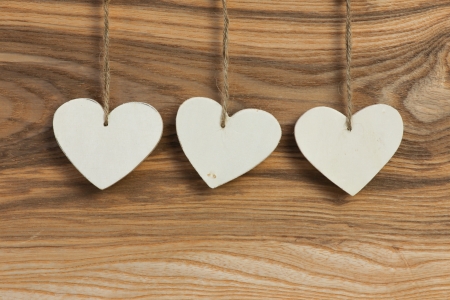 Three White Love Valentine s heart hanging on wooden texture backgroundの写真素材
