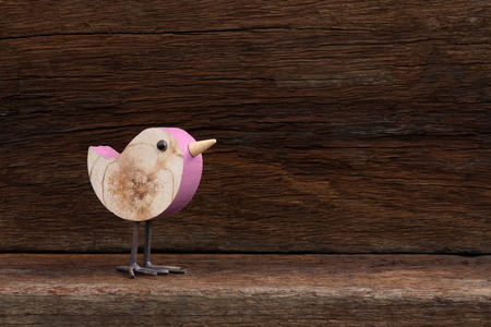 Wooden pink toy bird figure symbol on old rough background with copy spaceの写真素材