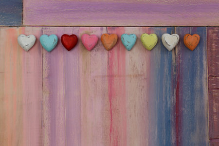 Love message space on colorful painted board with wooden hearts, copy space