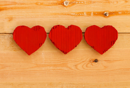 Love Valentines red painted recycled cardboard hearts on rough sawn pine boards background, copy spaceの写真素材