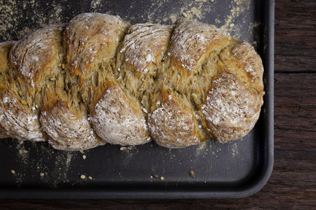 Freshly baked traditional sunflower seed three strand bread plait on backing tray
