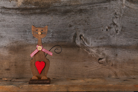 Valentines love brown wooden cat with red heart and gingham ribbon decoration on old rough grey background with copy spaceの写真素材