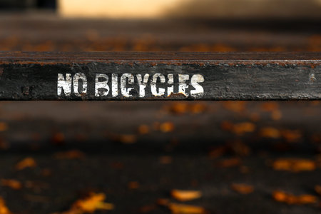 No bicycles white letters painted sign on old black rusty metal fence in Oxford, UK.