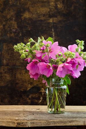 Pink hibiscus flowers bouquet in a vase on dark rustic backgroundの写真素材