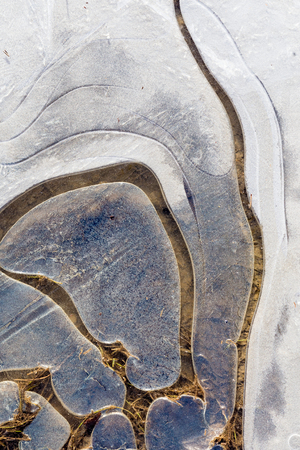Ice frozen puddle on the gravel country road surface winter backgroundの写真素材