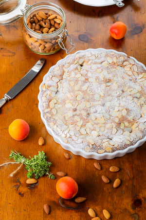 Crustless apricot frangipane tart with almonds and aromatic lemon thyme on rustic brown pine tableの写真素材