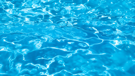 Bright Blue Water Surface Texture in Swimming Pool with Sunlight Reflectionsの写真素材