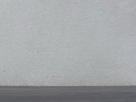 Minimalist Empty Textured White Wall with Dark Floor Background for Product Mockupの写真素材