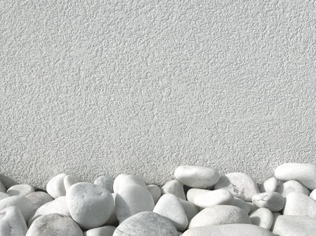 Sunlit Smooth White Pebbles at Base of Textured Wall Backgroundの写真素材
