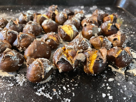 Golden Roasted Chestnuts with Cracked Shells and Sea Salt on Oven Trayの写真素材