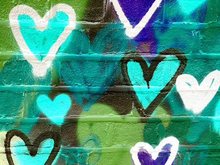 Teal and Green Heart Graffiti on Brick Wall with Bold Spray Paint Textureの写真素材