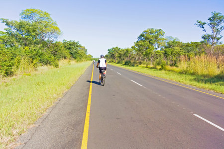 victoria Falls, Zambia - April 11, 2015: Man on bicycle cycling to the border between Zambia and Botswana.のeditorial素材
