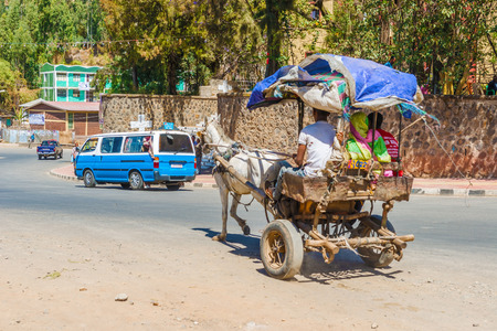 Gondar, Ethiopia - February 9, 2015: Street in Gondar in the early afternoon. Ethiopia. People riding in the cart pulled by donkey.のeditorial素材