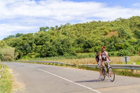 Songwe, Malawi - March 22, 2015: Local people riding bicycle on the road in Malawi near border with Kenya. Bicycle is a major source of transportation in Malawi.のeditorial素材