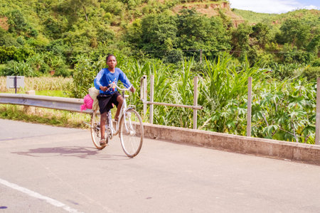 Songwe, Malawi - March 22, 2015: Local people riding bicycle on the road in Malawi near border with Kenya.のeditorial素材