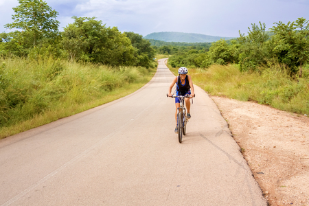 Chongwe, Zambia - April 1, 2015: Young woman on bicycle is cycling in Zambia near Chongwe.のeditorial素材
