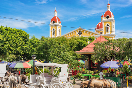 Granada, Nicaragua - November 20, 2016: Central Park and the towers of Granada Cathedral on the background. It is a neoclassical Catholic cathedral located in Granada. The church is the main temple of the Roman Diocese of Granada.のeditorial素材
