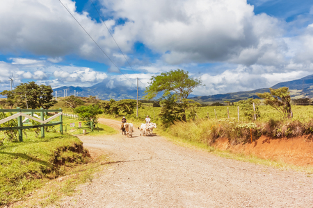 Tierras Morenas, Costa Rica - November 16, 2016: Picturesque mountain landscape with wind farm and farmers on the horses at the road near Tierras Morenas in Costa Rica.の写真素材