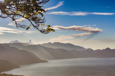 Picturesque landscape view at the lake Atitlan and the smoking, active volcano at the background, as seen from the road near Panajachel.の写真素材