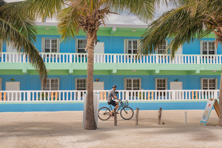 Caye Caulker, Belize - December 24, 2016: View at the hotel building and man riding bicycle on main street in Caye Caulker. It is a small island near Ambergris Caye, Belize.のeditorial素材