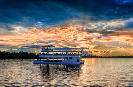 Picturesque sunset  landscape with the riverboat at Zambezi river near Livingstone in Zambiaのeditorial素材