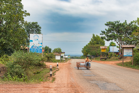 Ban Xenouan, Laos - November 6, 2017: Man riding bicycle on the main road through the small village of Ban Xenouan in Laos.のeditorial素材
