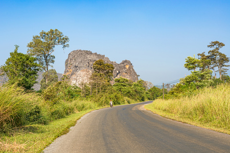 Na Hin,  Laos Nov 3, 2018: Man riding motor bike on the road by limestone forest near Na Hin in Laos.のeditorial素材