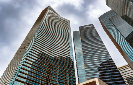 View from the street level at the glass, steel and concrete structures of skyscrapers in downtown Singapore.の写真素材