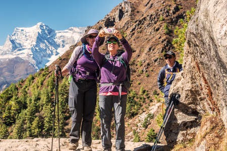 Namche Bazar, Nepal - October 28, 2018: Two young girls taking pictures when trekking in Himalaya to Everest Base Camp in Nepal.のeditorial素材