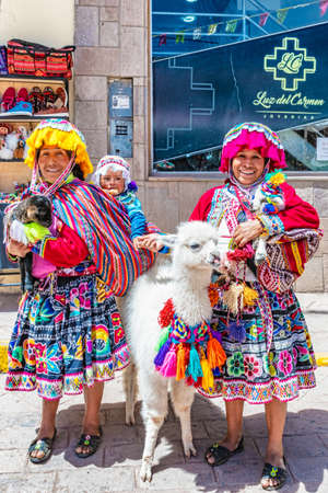 Pisaq, Peru - April 5, 2019: Women in traditional clothes with Alpaca on the street in Pisaq, Peru.のeditorial素材