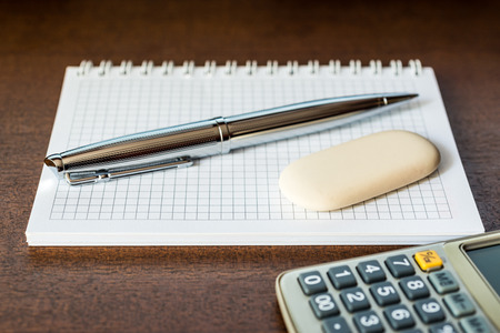 Calculator with a pen and eraser on the tableの写真素材