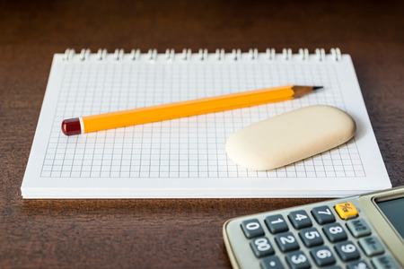 Calculator with a pencil and eraser on the tableの写真素材