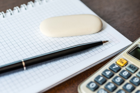 Calculator with a pen and eraser on the tableの写真素材